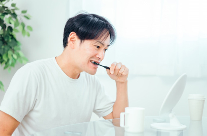 歯ブラシを握り歯を磨く40代男性