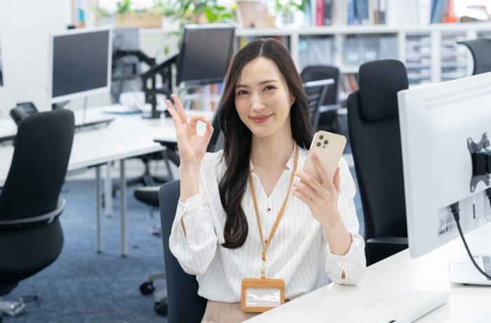 スマホを持ちOKサインをする会社員の女性