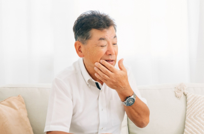お口に手を当て違和感を感じている様子の高齢男性