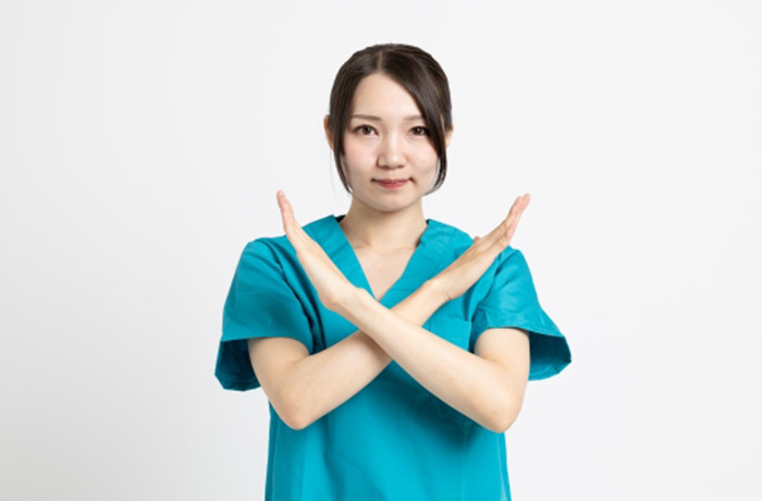 両手でバツをしてこちらを見ている歯科医師