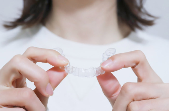 マウスピース矯正器具を手で持つ女性