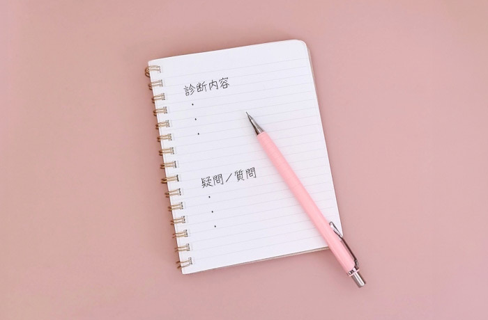 診療内容、質問内容という文字が書かれたノートとピンク色のシャープペン