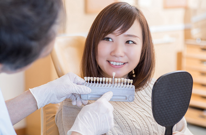 ホワイトニングについて歯科医にカウンセリングを受けている女性