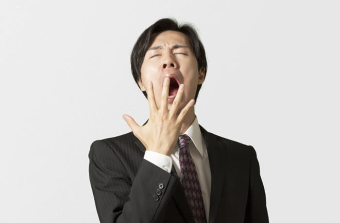 手で隠しつつも大きな口を開けてあくびをする男性の画像